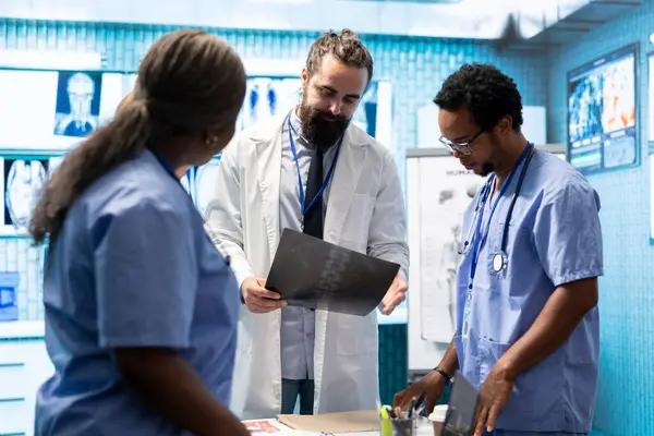 stock image Radiologists and osteopaths review x ray results and discuss treatment plans. Team of licensed diverse experts working in a private clinic to provide comprehensive medical services.