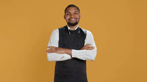 stock image Portrait of restaurant waiter wearing professional uniform and apron getting ready to assist and serve clients. Employee working in service oriented environment for customer satisfaction. Camera B.