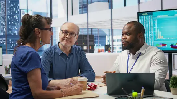 stock image Middle aged people receiving financial advice on retirement planning and life insurance, focusing on increasing their savings with pension plans. Senior couple meeting with banker. Camera B.