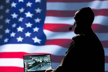 Birleşik Devletler ordu harekat subayı, ön saflarda savaşan komutanlara bilgi vermek için kulaklık mikrofonu kullanıyor. NATO askeri ABD bayrağı üzerinde izole edilmiş askerlere istihbarat sağlıyor.