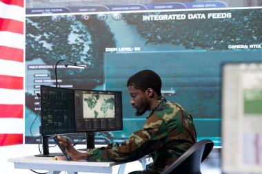 Amerikan askeri subayı yüksek teknolojili bir komuta merkezinde çalışıyor, gözetim sistemleriyle ulusal güvenlik operasyonlarını yönetiyor. İstihbarat toplamak için verileri inceliyorum..