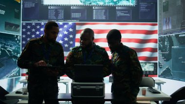 Yüksek teknoloji kontrol merkezindeki ordu subayı siber güvenlik operasyonlarına girişiyor, gizli verileri tehditlerden koruyor ve devlet sırlarını korumak için dijital savaş stratejilerini yönetiyor. Kamera B.