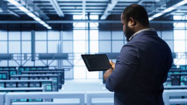 Veri merkezindeki bilgisayar bilimci hatayı düzeltmek için tablet üzerindeki araçları kontrol ederken hata yapıyor. Sunucu merkezi tesisinde IT uzmanı süper bilgisayarların performansını etkileyen ağ sorunları arıyor, kamera A