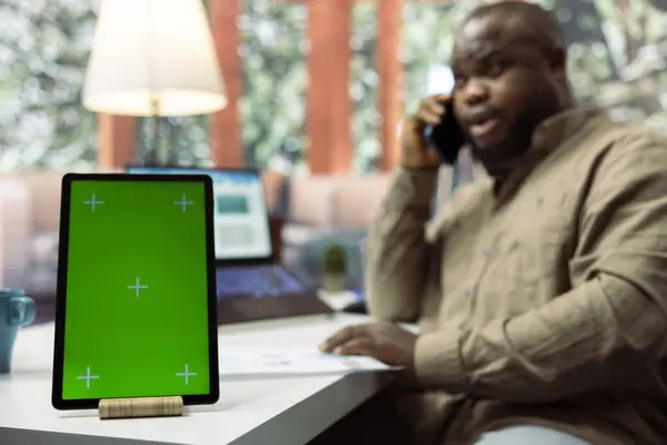 stock image Business owner chats on phone call with shareholders next to green screen, transmitting data analytics sales reports from his home desk. Entrepreneur negotiates the funding with investors.