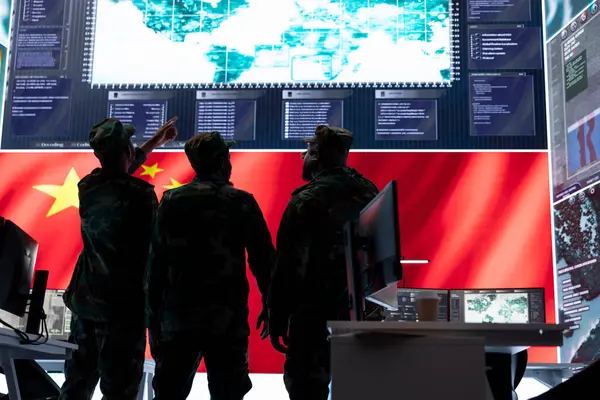 stock image Military intelligence officers from China analyze surveillance data on a big screen in a chinese command center. Soldiers discussing warfare tactics for a terrorist attack, high tech cyber network.