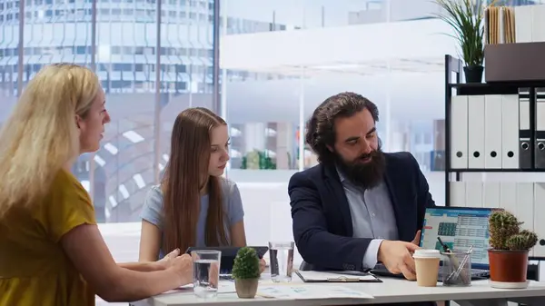 stock image Broker investor in office offering financial advice to clients, calculating their stock exchange profits. Financial advisor looking at market shares growth with customers, camera B