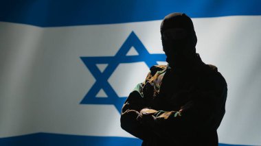 Mossad ajanı İsrail bayrağı önünde gururla duruyor, ülkesine hizmet etmekten gurur duyuyor. İsrailli Yahudi ordu mensupları savaş odasında silah çekiyorlar, milli marşı dinliyorlar, kamera B
