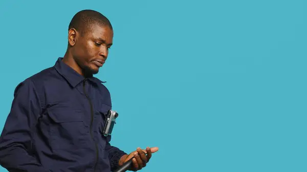 Stock image Security guard preventing criminal activity, threatening suspects with active bodycam. Portrait of menacing bodyguard pointing towards security body camera, studio background, camera A