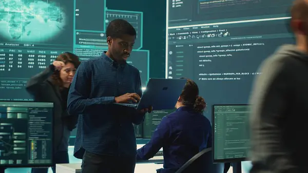 stock image Group of governmental hackers analyzing digital threats on pc networks, using a big screen. Specialists working on collecting information, fighting against cybercrime and cyberterrorism. Camera A.