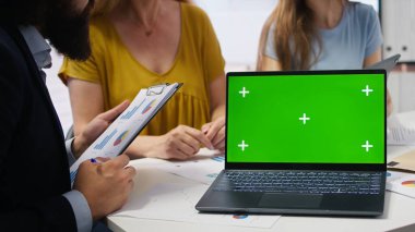 Müşteriler toplantı sırasında finans danışmanı tarafından yazılan yeşil ekran dizüstü bilgisayarda kişisel planlama rehberine bakıyorlar. A kamerasıyla müşteriler için yaşam giderlerini optimize eden danışman.