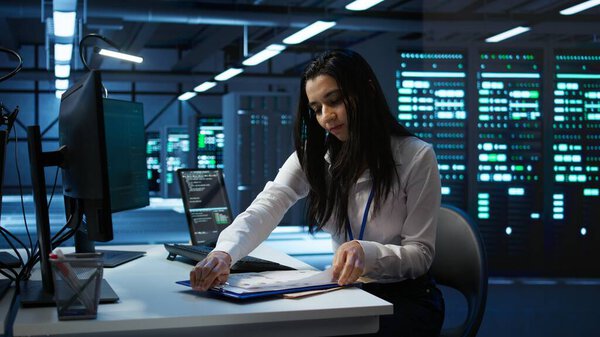 Engineer in data center installing software on computer, helping maintain network, troubleshooting arising issues. IT expert in server room establishing performance benchmarks, camera B