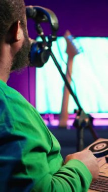 Vertical Video kendinden emin müzik mühendisi ev stüdyosunda konsol karıştırma üzerinde çalışıyor, bir şarkı için yeni sesler üretiyor ve daw yazılımında ses düzeylerini düzenliyor. Ses teknisyeni akustik dosyaları kaydediyor