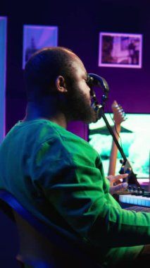 Ana stüdyoda profesyonel prodüksiyon yazılımı kullanarak bir proje için yeni bir film müziği besteleyen dikey video Afrikalı Amerikalı sanatçı. Müzik üreten ve ses efektleri ekleyen yetenekli yaratıcı şarkıcı.