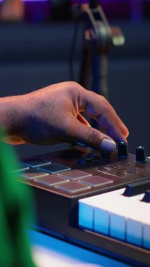 Vertical Video Müzik Mühendisi, ses konsolunda melodileri karıştırarak ve ustalaştırarak şarkı üretiyor, synthesizer 'da sesleri kaydetmek için piyano notaları çalıyor. Yapımcı Midi ile film müzikleri yapıyor