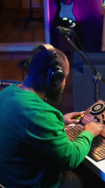 Dikey Video Yetenekli Müzisyen, miksaj konsolunda ses ekipmanlarıyla çalışan yeni ses müzikleri yaratıyor. Ses teknisyenleri melodisinin ses seviyesini düzenlemek için düğmeleri çeviriyor. Kamera B.