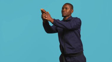 Güvenlik görevlisinin portresi mülke izinsiz girilmesini önlemek için ateş ediyormuş gibi yapıyor. Özel güvenlik görevlileri tabancayla el hareketi, stüdyo arka planı, kamera B