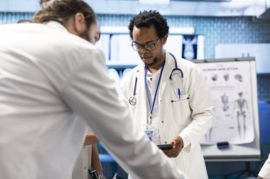 Çeşitli doktorlar hastane kayıtlarını ve röntgen sonuçlarını inceliyor. Doğru tanıyı koymak için tomografi ve radyografiye bakıyorlar. Uzmanlar hastalıkların önlenmesini sağlamak için takım çalışması yapıyorlar.