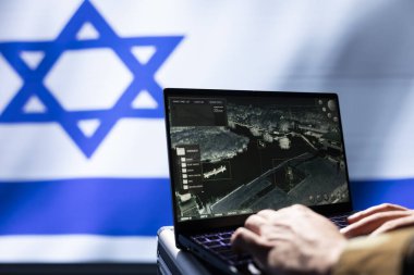 İsrailli IDF ordu uzmanı, düşman konumunu tespit etmek için bilgisayardaki hedef yakalama teknolojisini kullanıyor. Yakın çekim. MOSSAD ajanı uydu aygıtı kullanarak İsrail bayrağı üzerinde izole edildi