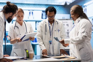 Tıbbi uzmanlardan oluşan bir ekip, bir hastalık için tedavi sağlamadan önce x ışını test sonuçlarına ve sağlık kayıtlarına bakıyorlar. Klinikte hızla iyileşmesini sağlayan yetenekli doktorlar..