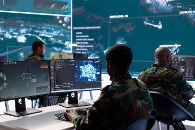 Görev kontrol merkezindeki askeri profesyoneller uydu görüntülerini ve verilerini analiz etmek, tehditleri izlemek ve istihbarat operasyonlarını desteklemek için modern teknolojiyi kullanıyorlar. Gözetim sistemi.