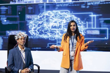 Portrait of IT experts talking at AI summit, sharing neural implants industry insights to audience. Engineers at artificial intelligence event presenting latest AI EEG headsets, doing demonstration clipart