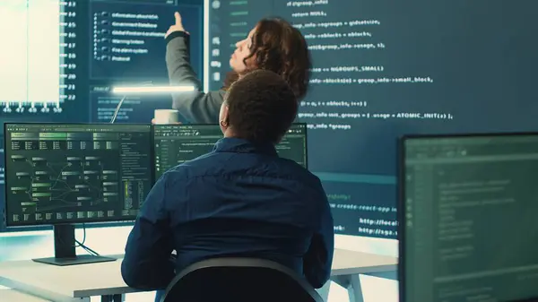 stock image Governmental hackers analyzing data for cyber threat detection, looking at a big screen in high tech office. Highlight cyber intelligence, online security and prevention of digital threats. Camera A.