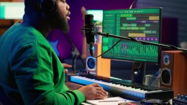 Müzisyen yeni melodisini mikrofonda söylüyor, kayıtları karıştırma ve ana tekniklerle manipüle ediyor. Yeni bir parça besteleyen genç şarkıcı, stereo ekipmanlar. Kamera A.