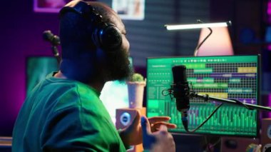 Sanatçı yapımcı mikrofonda kayıt için yeni bir şarkı söyleyerek, post prodüksiyonda müziği düzenlemeye hazırlanıyor. Ses kayıt dosyalarına karıştırma ve ustalaşma teknikleri uygulayan bir müzisyen uzmanı. Kamera A.