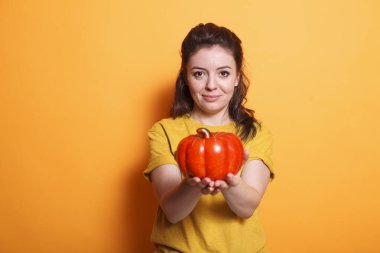 Kırmızı dolmalık biber tutan sağlıklı bir kadının portresi. Olumlu kadın vegan ve organik beslenme uzmanı taze çiğ sebze sergiliyor ve vejetaryen diyetini vitaminlerle sunuyor..