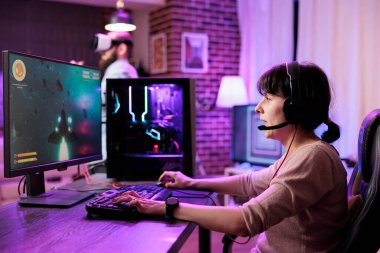 Oyuncu çevrimiçi esport maçları oynarken rahatsız edici gecikmeden kaçınmak için profesyonel seviye oyun bilgisayarı kullanıyor. Gecenin geç saatlerinde neon ışıkları altında dinlenen bir kadın video oyunu oynuyor.