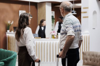 Bavulları olan beyaz, yaşlı bir çift lüks salona geliyor. Emekli kıdemli yetişkinler resepsiyonistlerle görüşmek için danışmaya gelirler. Otel lobisi davetkar, dinlenmek için mükemmel..