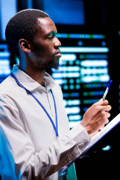 stock image Expert conducting diagnostic tests on server racks to identify and rectify issues with data center equipment. Admin meticulously reviewing maintenance checklist, closely monitoring critical systems