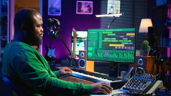 stock image Songwriter mixing and mastering tracks on stereo console, playing electronic keyboard in home studio. Artist oversees audio performances to create melody, producing tunes with piano keys. Camera B.