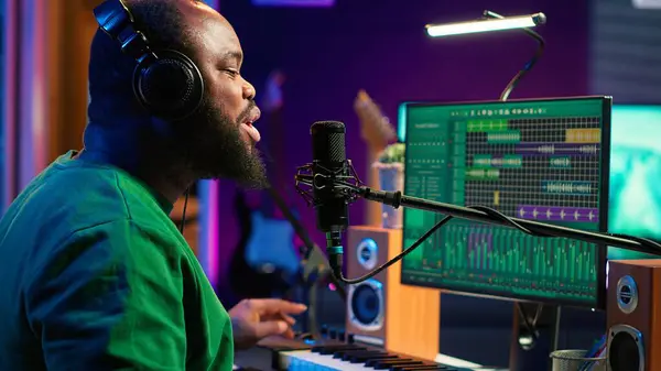 stock image Musician singing his new melody creation on microphone, manipulating his recordings with mix and master techniques. Young artist singer composing a new track, stereo equipment. Camera A.