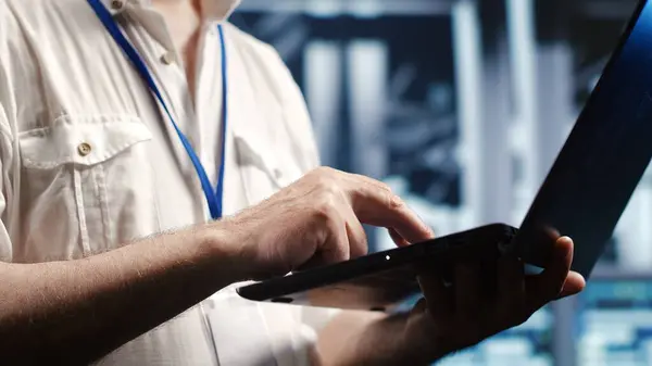 stock image Hardworking professional navigating network of server devices in industrial hub. IT practitioner with laptop doing optimizations and maintenance in data center, preventing system damages, close up