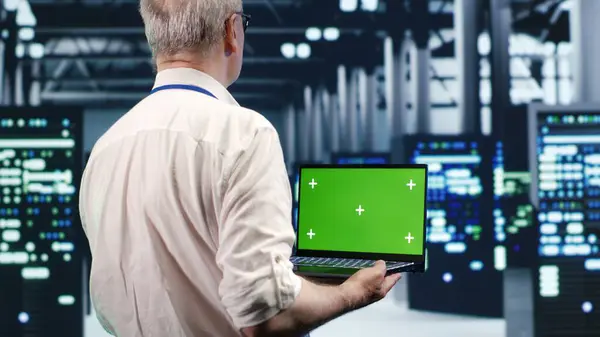stock image Efficient IT professional navigating network of server rigs in industrial hub. Expert using mockup laptop, ensuring proper operations, doing optimizations and maintenance in data center