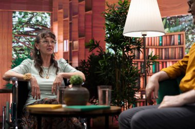 Tekerlekli sandalyedeki yaşlı kadın evde yaşlı bir adamla gülüyor ve sohbet ediyor, bağ kuruyor ve birlikte eğleniyorlar. Kocasıyla keyifli bir etkileşim içinde olan engelli bir insan..