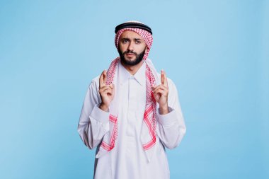 Kültürel Müslüman kıyafetleri giyen bir adam batıl inançlı ve umut dolu bir ifadeyle şans diliyor. Geleneksel ortopedi ve ghutra giymiş Araplar dilek ve iyi şanslar diliyorlar.