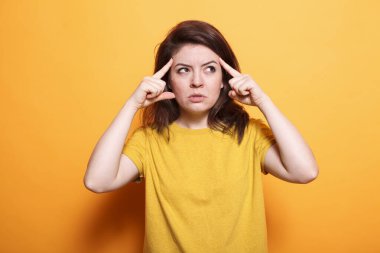 Yoğunlaşan ve düşünen, hayal gücünü kullanmayı düşündüğü için işaret parmaklarıyla alnına dokunan kadın. Motive edici derin düşünceleri olan genç bir kadının portresi.