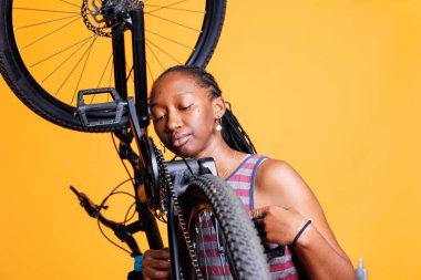 Sports-loving African American female expertly maintains and repairs her bike and adjusting components. Young black woman with meticulous attention to detail ensures optimal performance and longevity. clipart