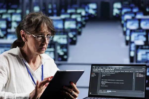 stock image Old computer scientist writing script code in data center on laptop terminal. Adept professional doing maintenance work in server room, updating rigs software to prevent malfunctions