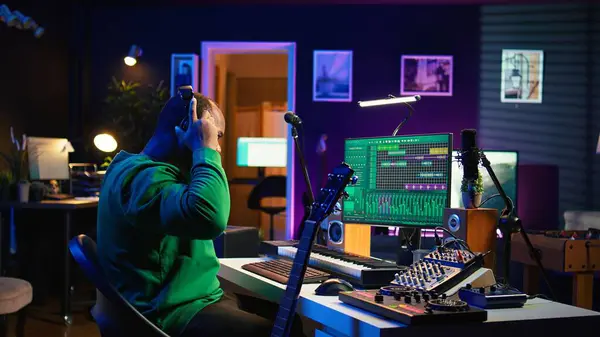 stock image Producer composing new music on acoustic instrument in home studio, using microphone to sing chords. Musician songwriter works with mixing console and software, guitarist producing tunes. Camera B.