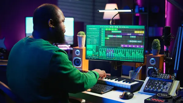 stock image Audio engineer recording and producing new tunes on professional pc software, using mixing console and midi controller to create new music. Artist composer uses stereo gear at home studio. Camera B.