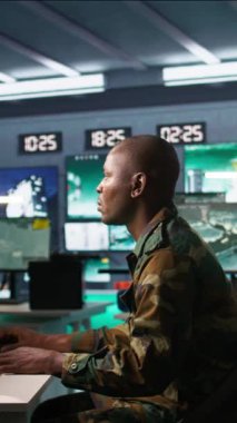 Askeri üste dijital radar ekipmanları ve çalışan füze sistemleri ile gözetleme yapan dikey video istihbarat ajanı. Afrika kökenli Amerikalı bir adam, yetkisiz kişiler için ordu merkezinin güvenlik kameralarını izliyor.