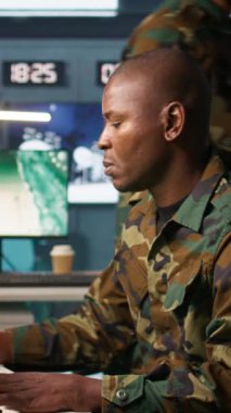 Kontrol odasında çalışan askeri ajanın dikey video portresi hava keşif verilerini analiz ediyor. İstihbarat Teşkilatı ajanı İHA 'ları kontrol ediyor stratejik hedeflere saldırıyor, Kamera B