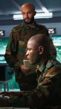 Komuta merkezindeki askeri subaylardan oluşan dikey video ekibi düşman savaş düzeni hakkındaki istihbarat dosyalarına bakın. İstihbarat teşkilatı meslektaşları muhalifler hakkında bilgi toplamak için görev dosyasını okuyor.