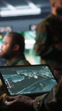 Tablet üzerinde uydu yazılımı kullanarak muharebe desteği sağlayan dikey video ordu telekomünikasyon sistemi operatörü. Taşınabilir cihaz ve kamera ile iletişim ağlarını yöneten askeri sevkiyat memuru