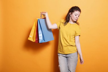 Kara Cuma mağazasından aldığı ürünlerden sonra renkli paketler taşıyan günlük kıyafetler giyen şık bir kadın. Beyaz kadın kameranın önünde poz verirken alışveriş torbalarını tutuyor..