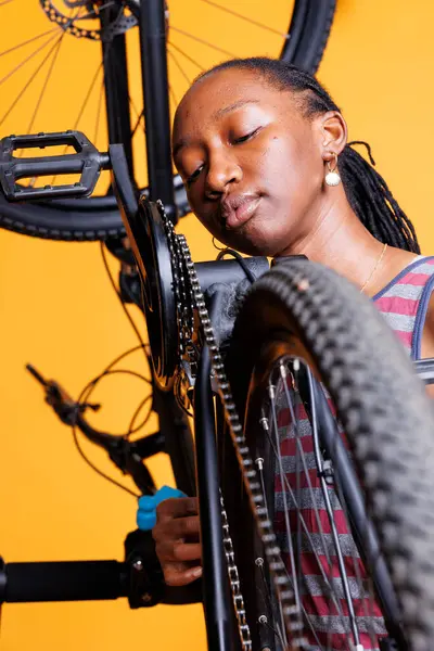 stock image African American lady sports enthusiast efficiently maintains and repairs bike, as well as modifying components. Healthy black lady with a keen eye for detail assures peak performance and longevity.