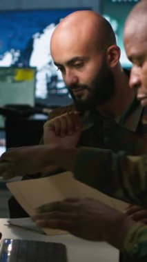 Komuta merkezinde beyin fırtınası yapan dikey ordu subayları istihbarat dosyalarına bakıyorlar. İstihbarat uzmanları karşı tarafın stratejisi hakkında bilgi almak için görev dosyalarını okudular.